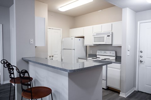 A kitchen with a fridge and a microwave and oven.
