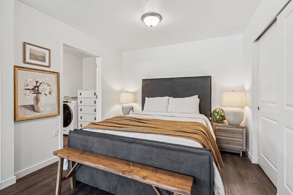 A bedroom with a bed, nightstand, and a painting on the wall.