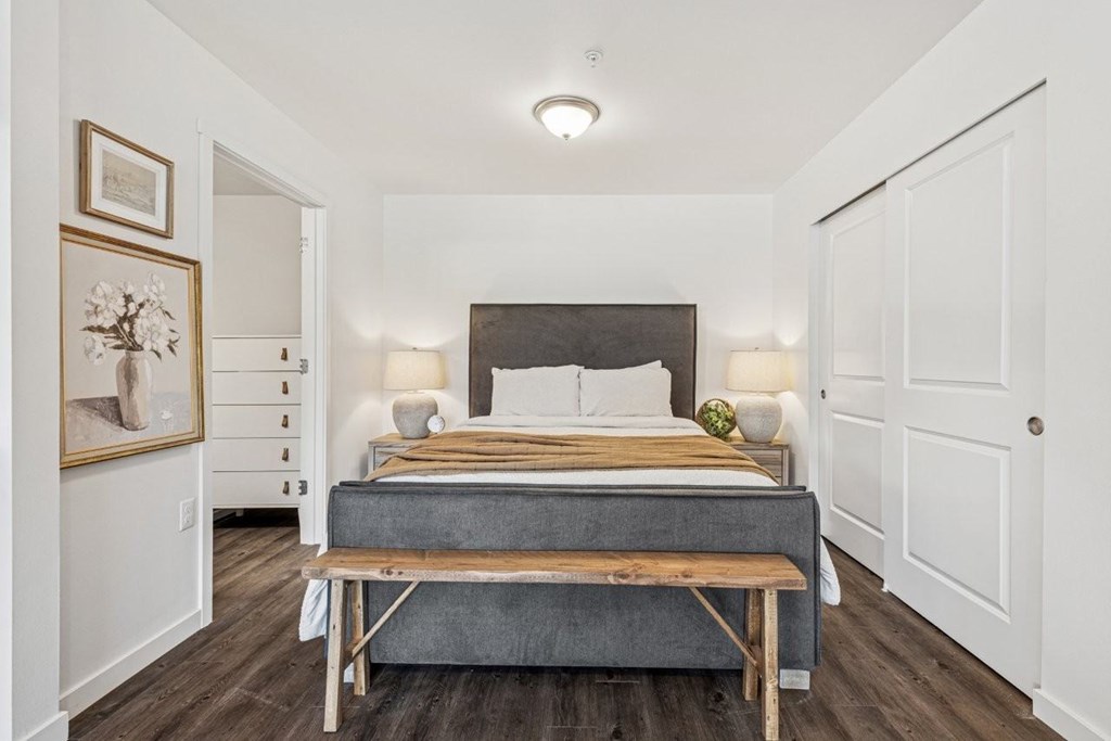 A bedroom with a bed, nightstands, and a bench.