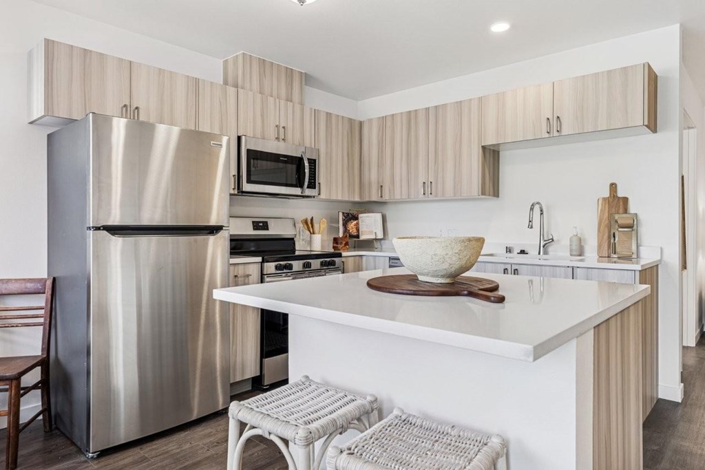 A modern kitchen with a stainless steel refrigerator and a white countertop.
