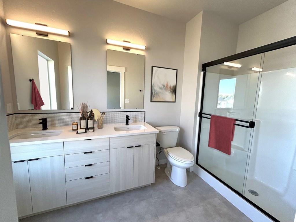 A bathroom with a white toilet, sink, and a red towel hanging on the glass door.