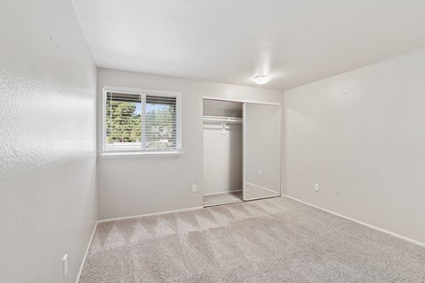 A room with a carpeted floor and a window with blinds.