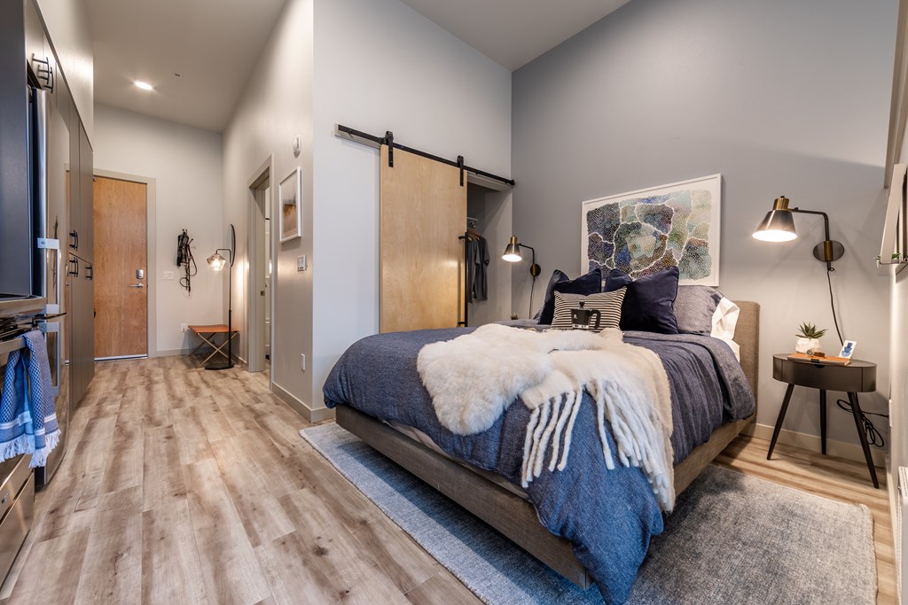 A bedroom with a bed covered in a blue comforter and a white fur throw.