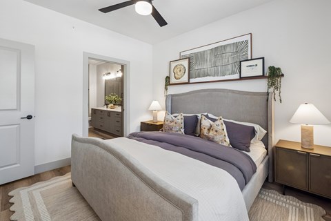 A bedroom with a large bed and a ceiling fan.