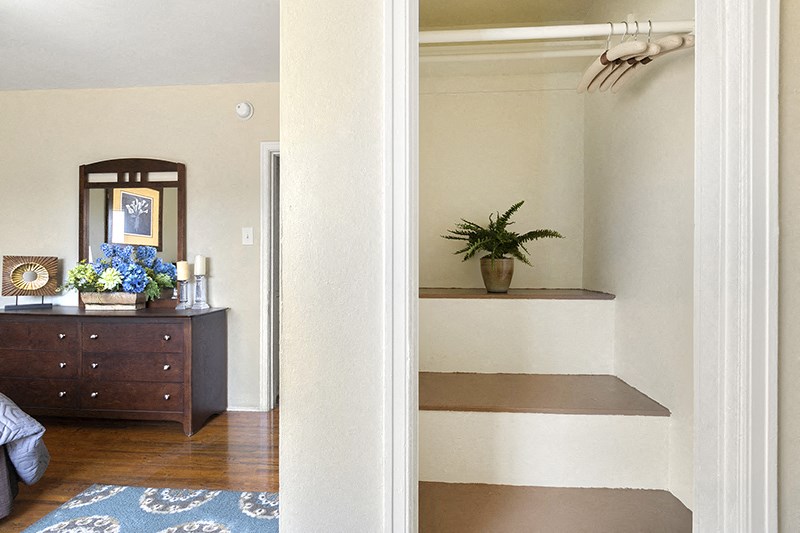 a bedroom with white walls and a dresser with a plant on it