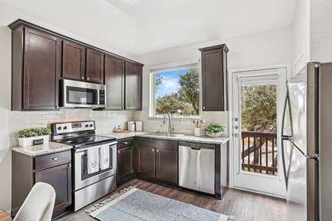 A kitchen with dark brown cabinets and stainless steel appliances.