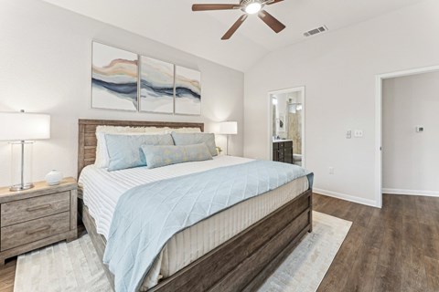A bedroom with a bed, nightstand, and a painting on the wall.