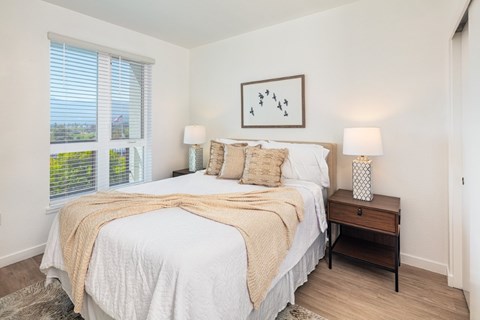 A bedroom with a large bed and a painting on the wall.