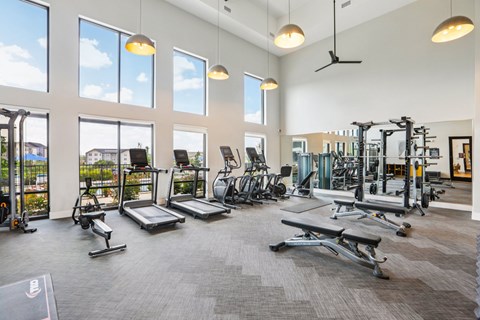 A spacious gym with a variety of equipment and large windows.