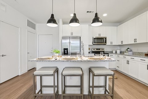 A kitchen with white cabinets and a center island with two stools.