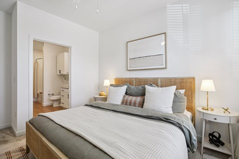 A bedroom with a large bed and a small table with a lamp.