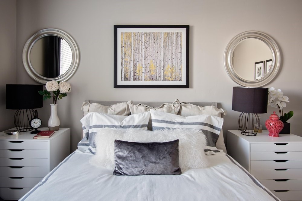 A bedroom with a large bed, two nightstands with lamps, and a framed picture on the wall.