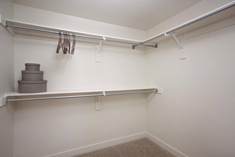 A white wall with a silver rod and a set of silver hooks.