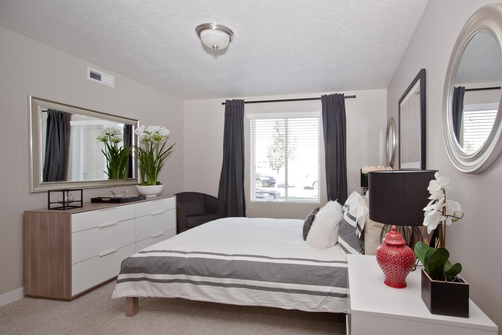 A bedroom with a bed, nightstand, and a mirror on the wall.