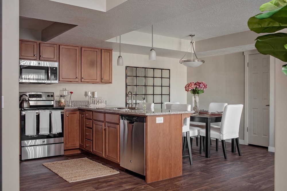 A kitchen with a wooden island and white chairs.