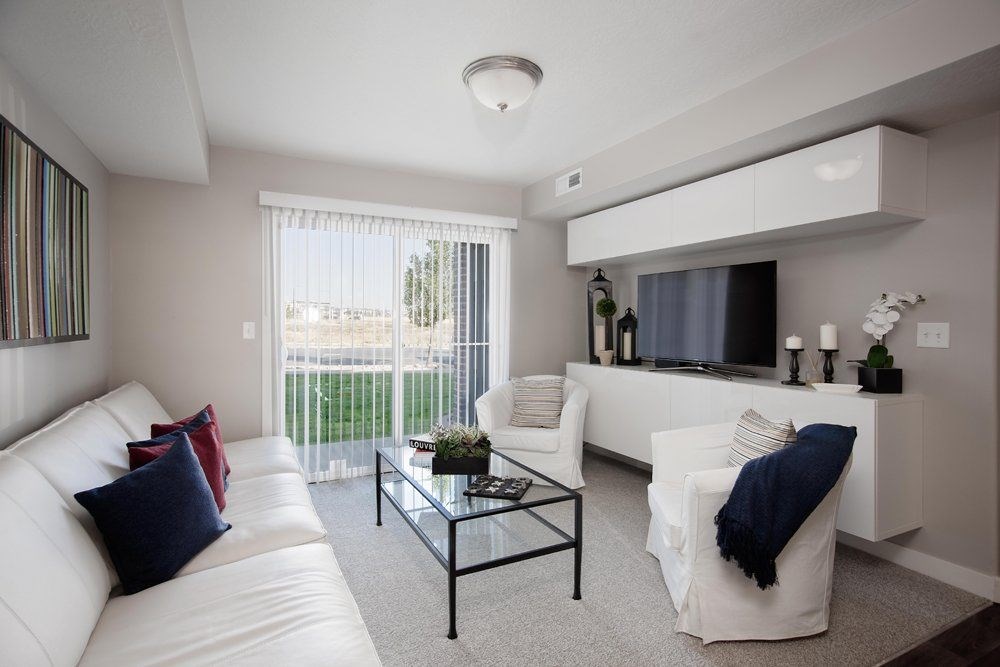 A modern living room with a white couch, a glass coffee table, and a flat-screen TV.