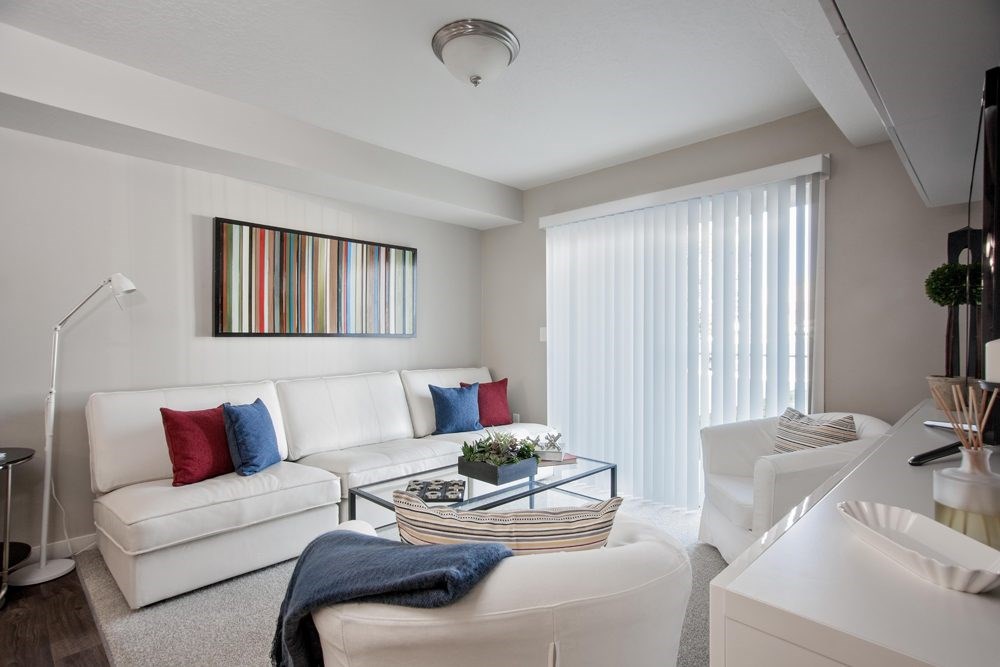A living room with a white couch and a striped painting on the wall.