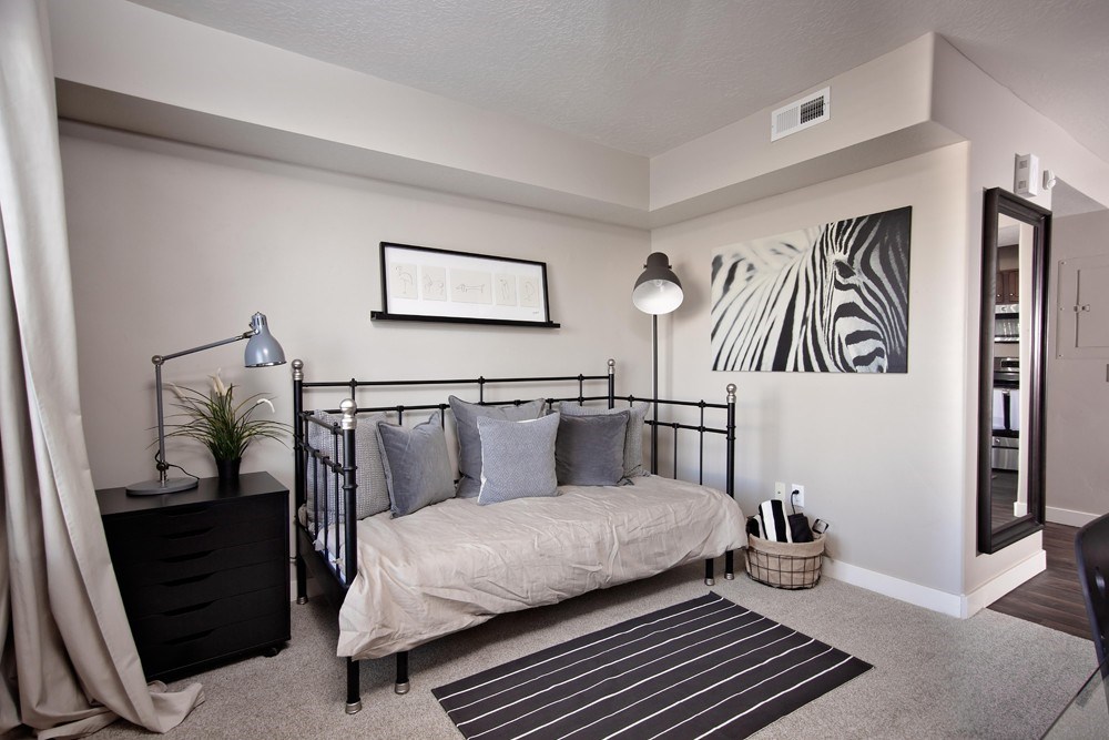 A bedroom with a bed, nightstand, and a painting on the wall.