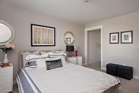 A bedroom with a large bed and two framed pictures on the wall.