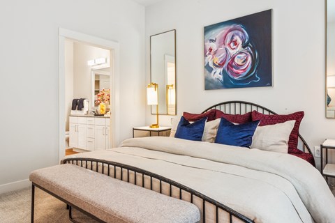 A bedroom with a large bed and a painting on the wall.