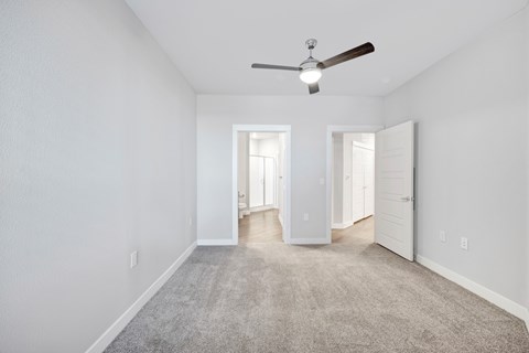 A spacious room with a ceiling fan and carpeted floor.