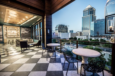 a balcony with a view of a city and tables and chairs