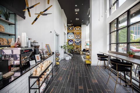 the interior of a coffee shop with tables and chairs and large windows