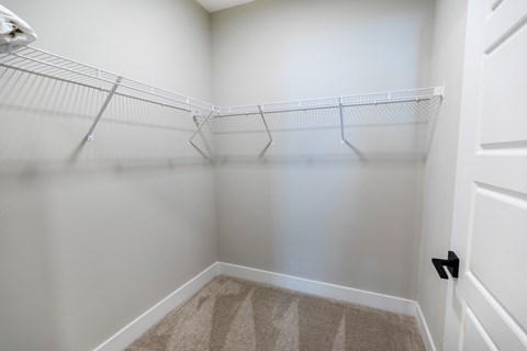 an empty closet in a home with white walls and a white door