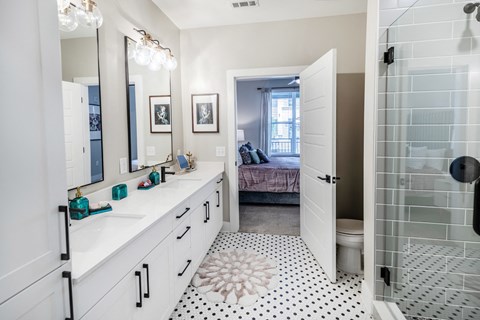 a bathroom with two sinks and a shower and a bed