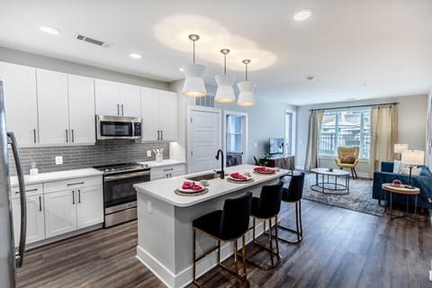 a kitchen with white cabinets and a white island with black chairs