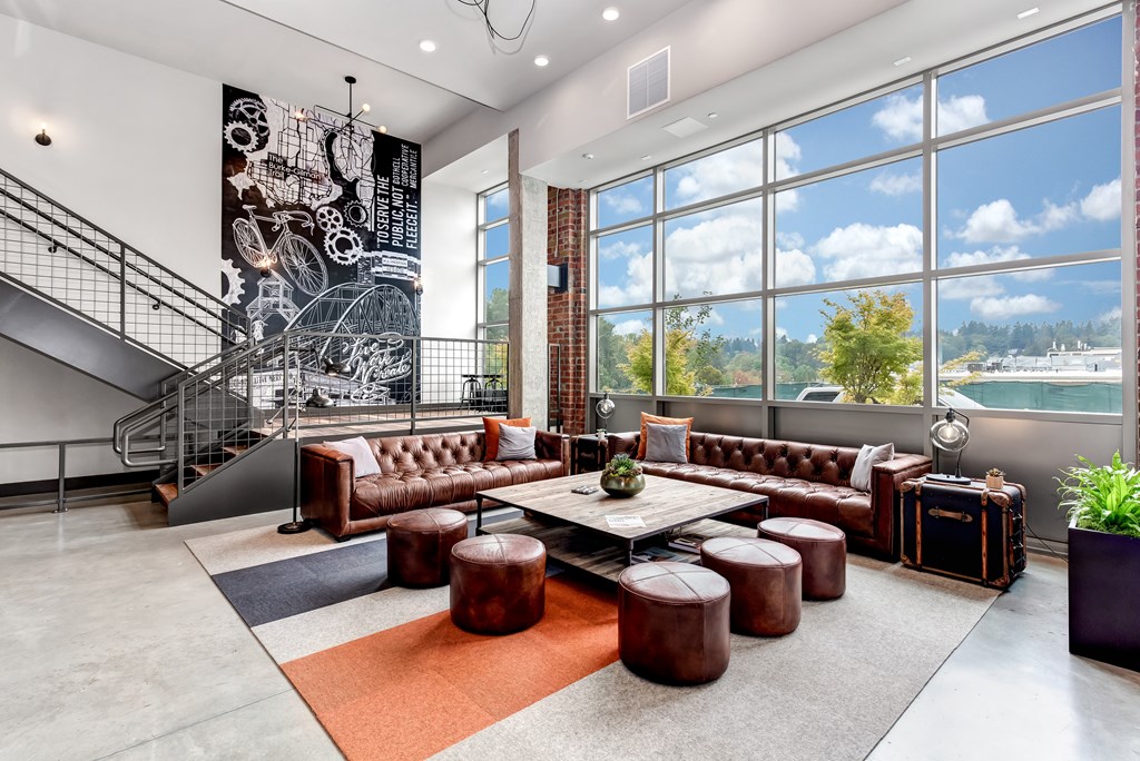 A modern living room with a staircase and a large window overlooking a landscape.