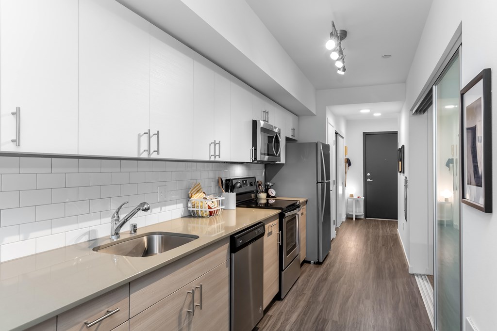 A modern kitchen with wooden floors and stainless steel appliances.