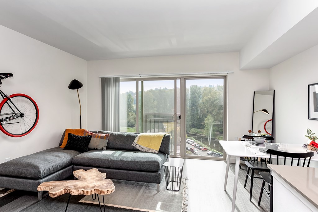 A living room with a grey couch and a bicycle on the wall.