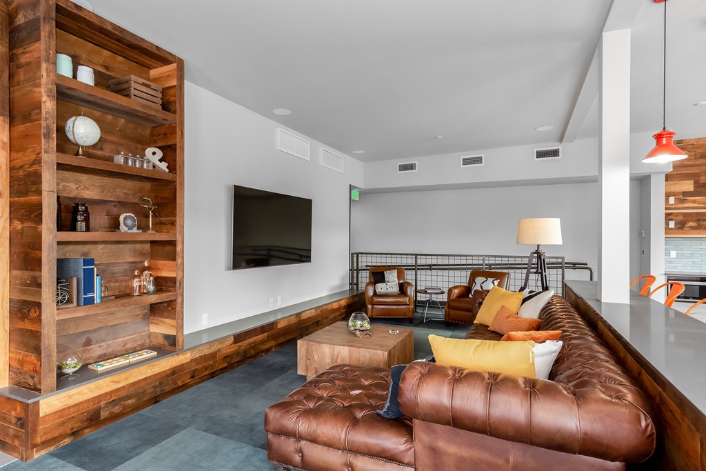 A living room with a brown leather couch and a wooden bookshelf.