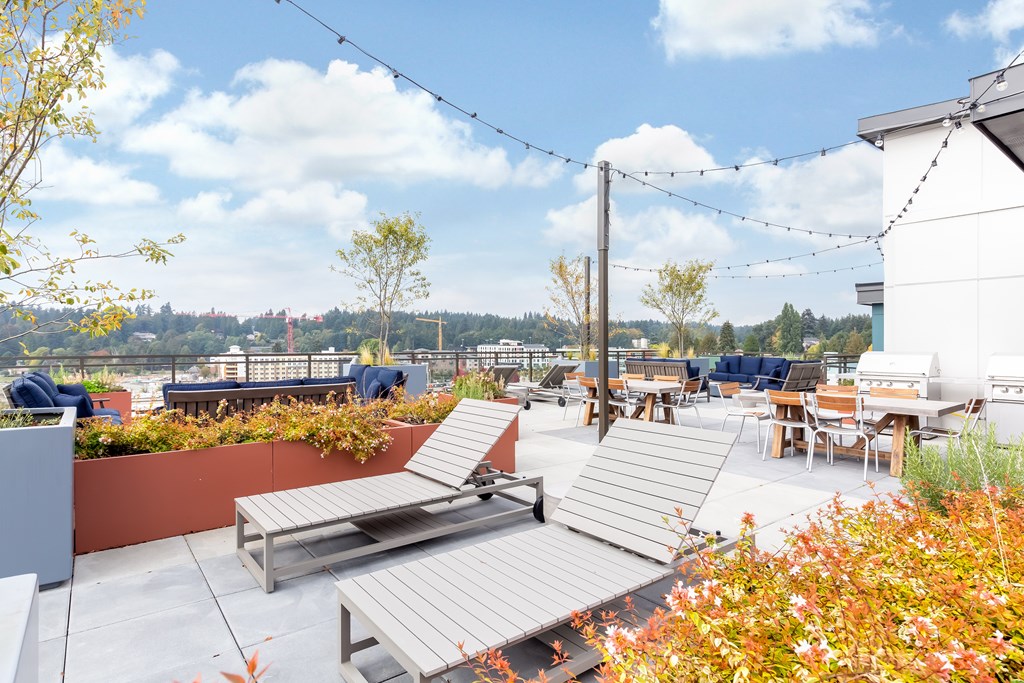 A rooftop patio with a bench, chairs, and a table.