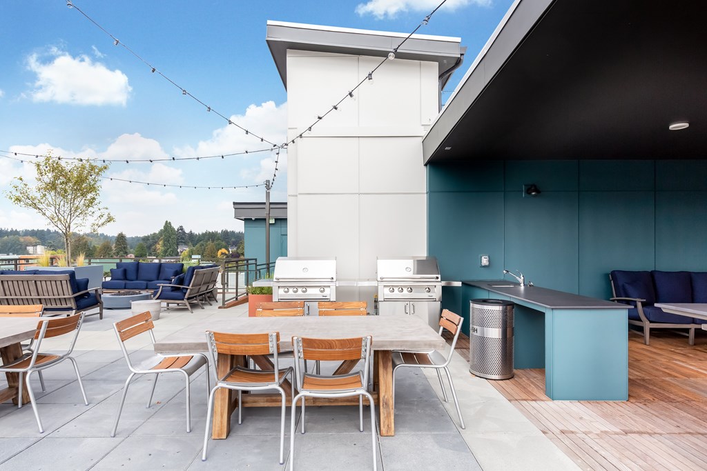 A patio with a table and chairs and a grill.
