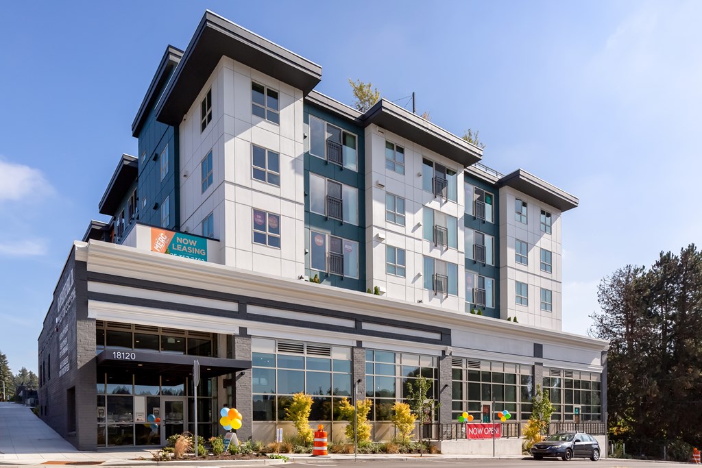 A modern building with a glass entrance and a sign that says "Now Open".