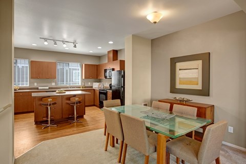 A modern kitchen with a glass dining table and chairs.