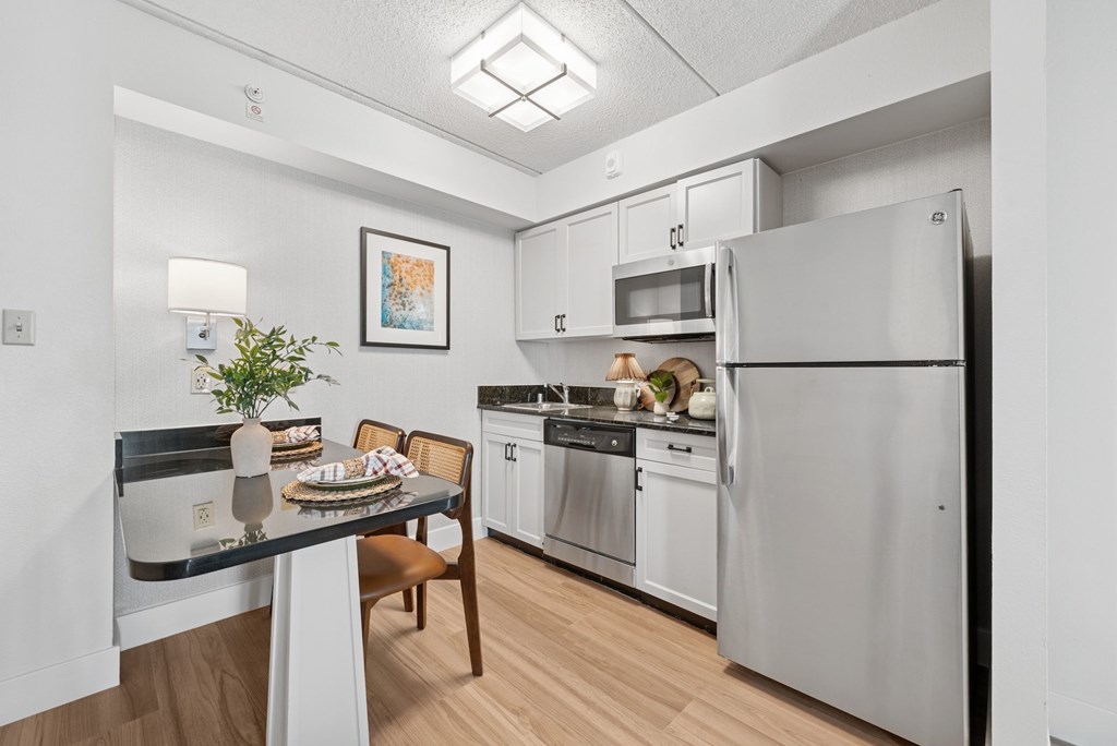 A kitchen with a table and chairs and a refrigerator.
