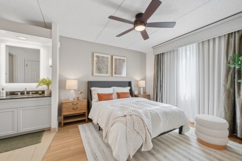 A bedroom with a bed, a ceiling fan, and a nightstand with a lamp.