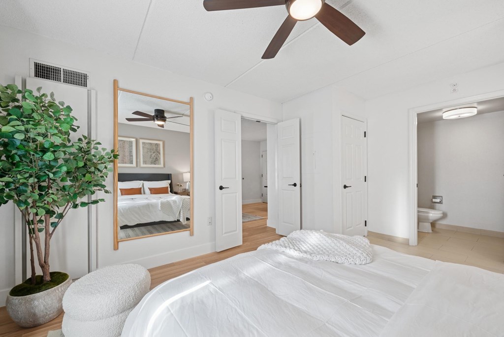 A white bedroom with a large bed and a ceiling fan.