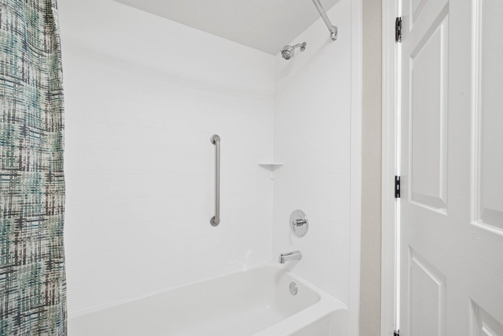 A white bathroom with a shower and a door.