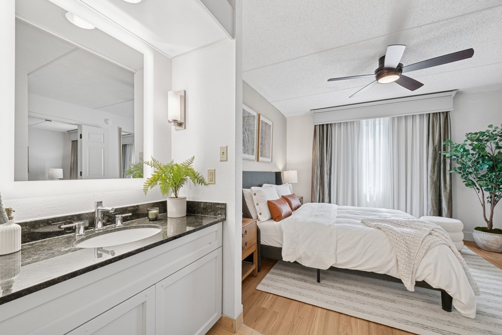 A bedroom with a bed, a sink, and a ceiling fan.