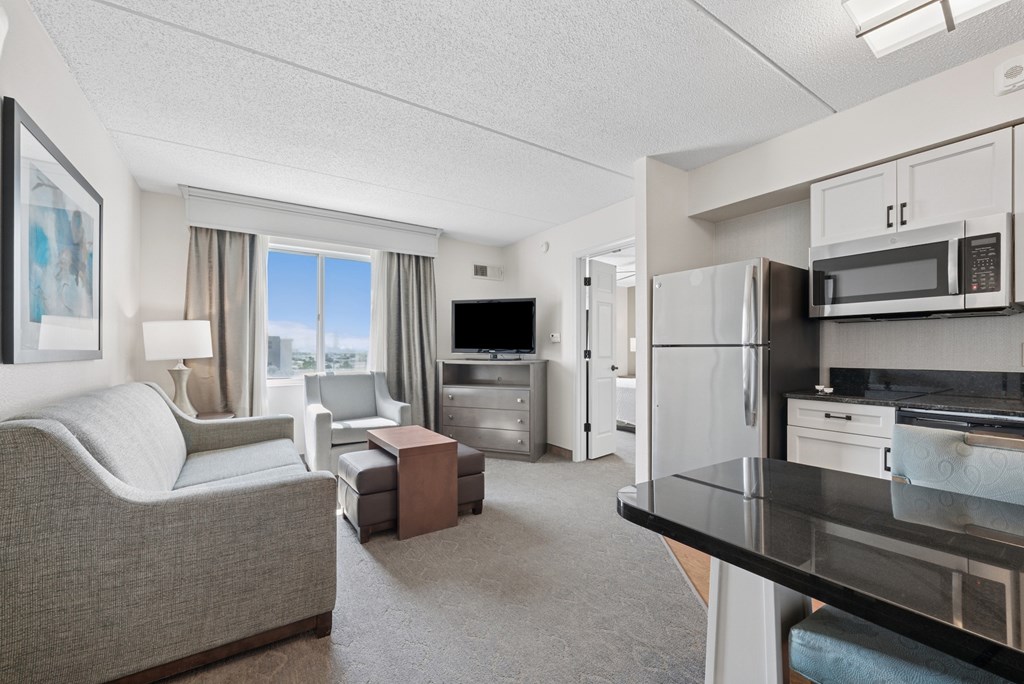 A well-lit, modern kitchen and living room with a grey sofa and a coffee table.