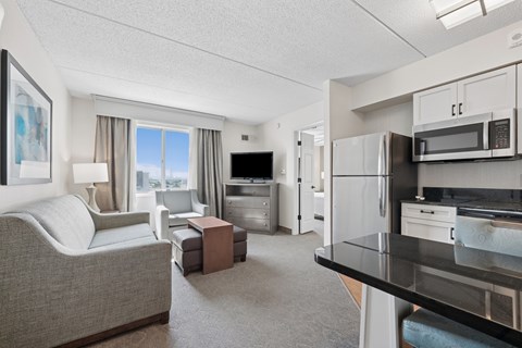 A well-lit, modern kitchen and living room with a grey sofa and a coffee table.