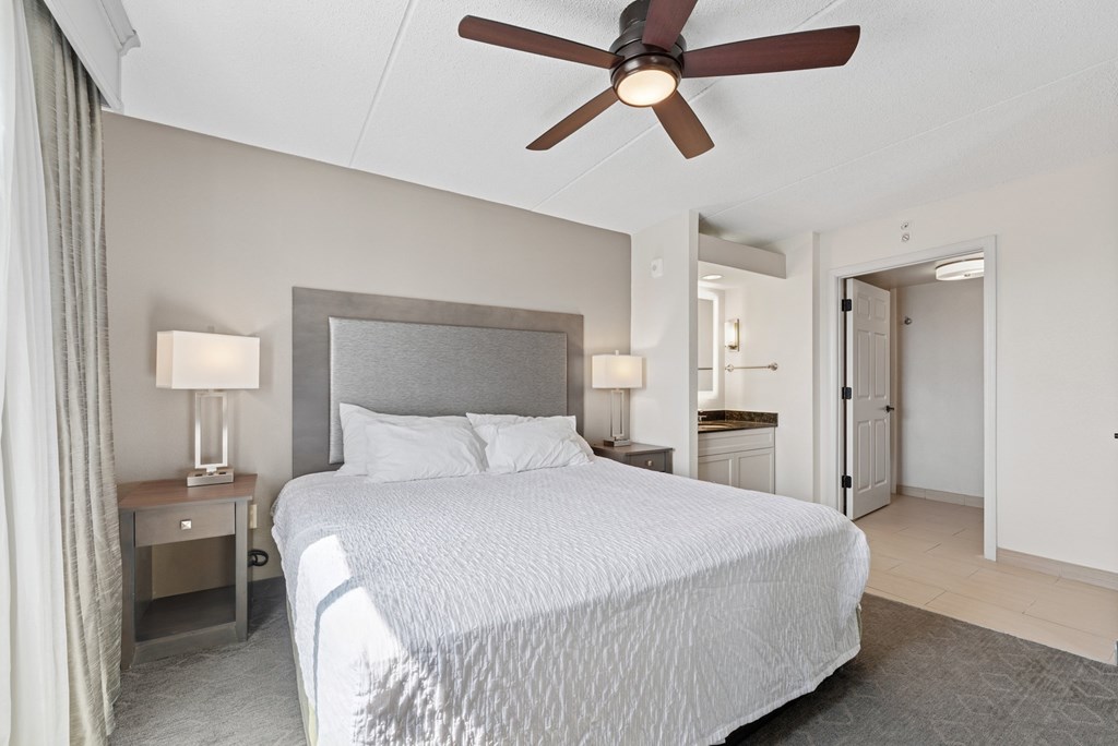 A bedroom with a large bed and a ceiling fan.