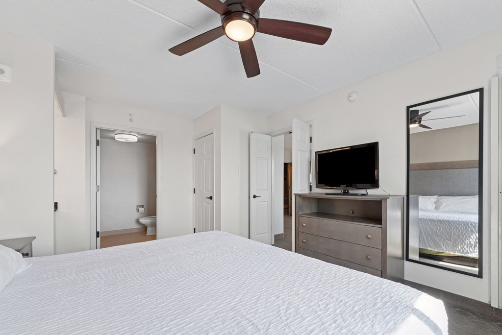 A bedroom with a bed, dresser, and television.