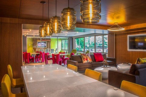 A modern dining area with a long table and colorful chairs.