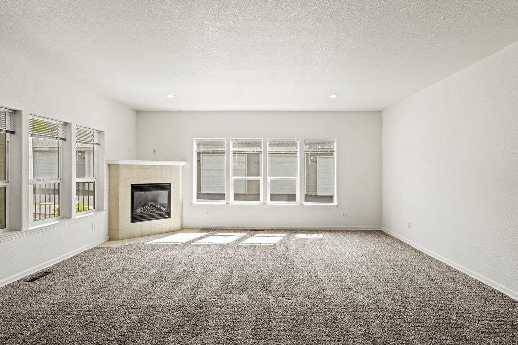 an empty living room with a fireplace and windows