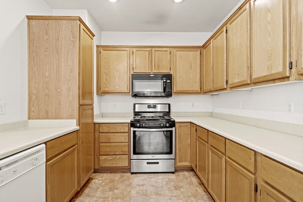 a kitchen with white countertops and wooden cabinets